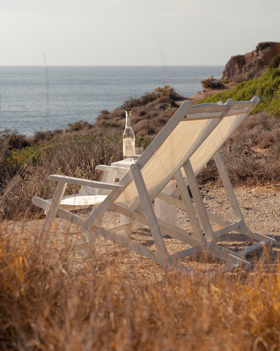 Deck chair on a coastal cliff with a bottle of Saint Rhum