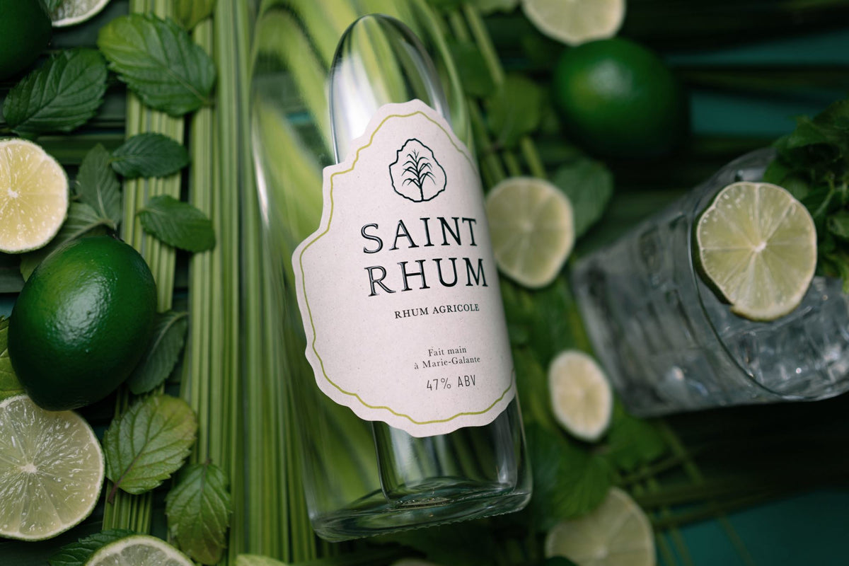 A bottle of Saint Rhum lying among fresh sugarcane and halved limes