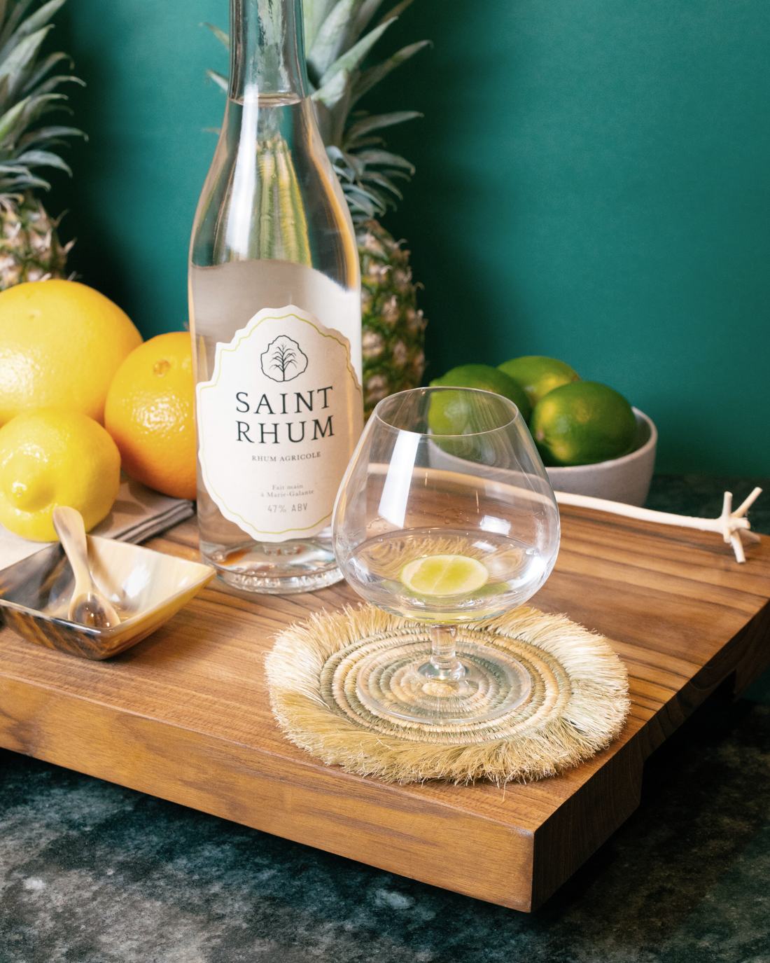 Saint Rhum and a glass beside lemons, limes and pineapple